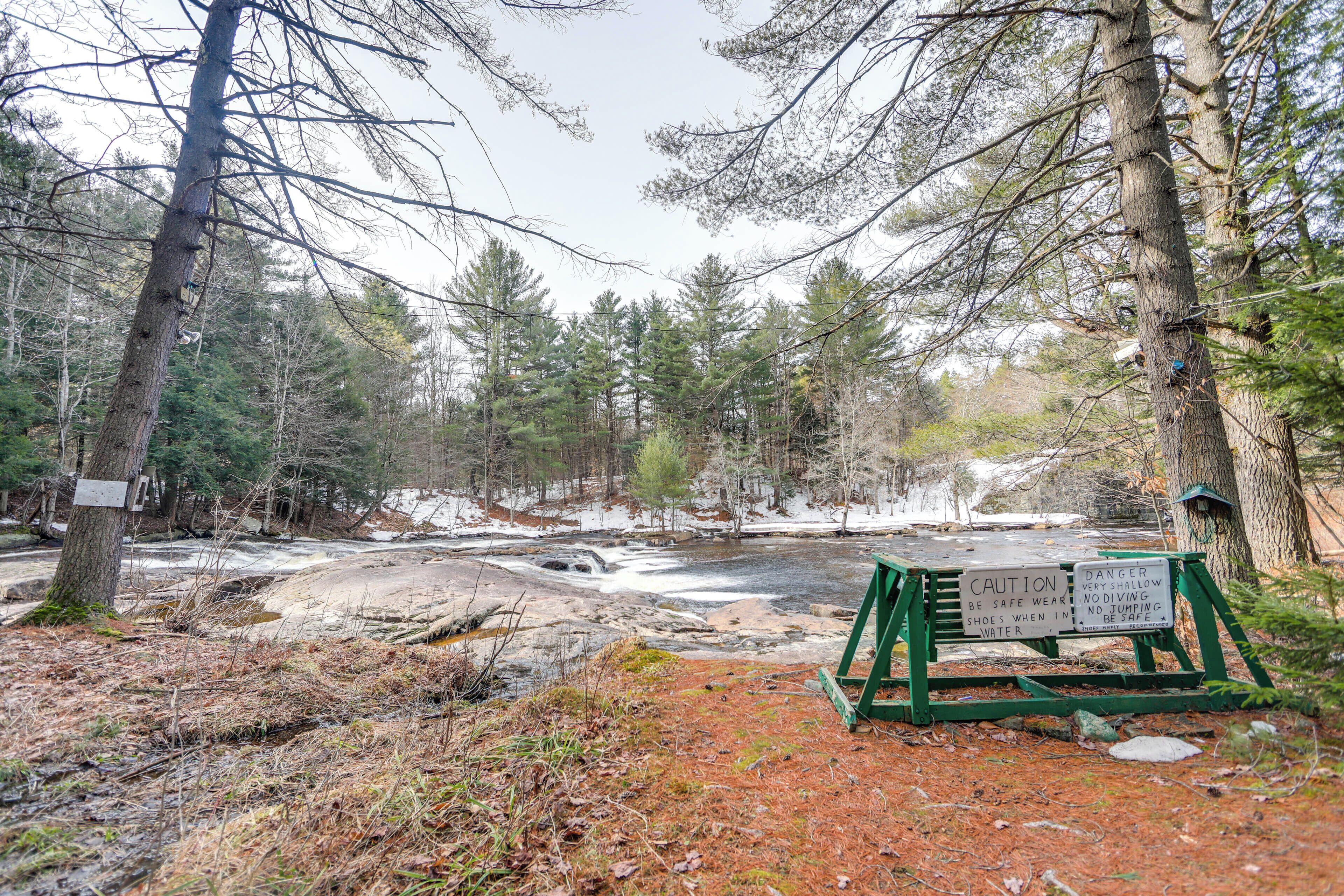 A forested area with a wooden signboard and a bench.