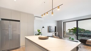 A modern kitchen with a large island, stainless steel appliances, and a large window offering a view of the outdoors.