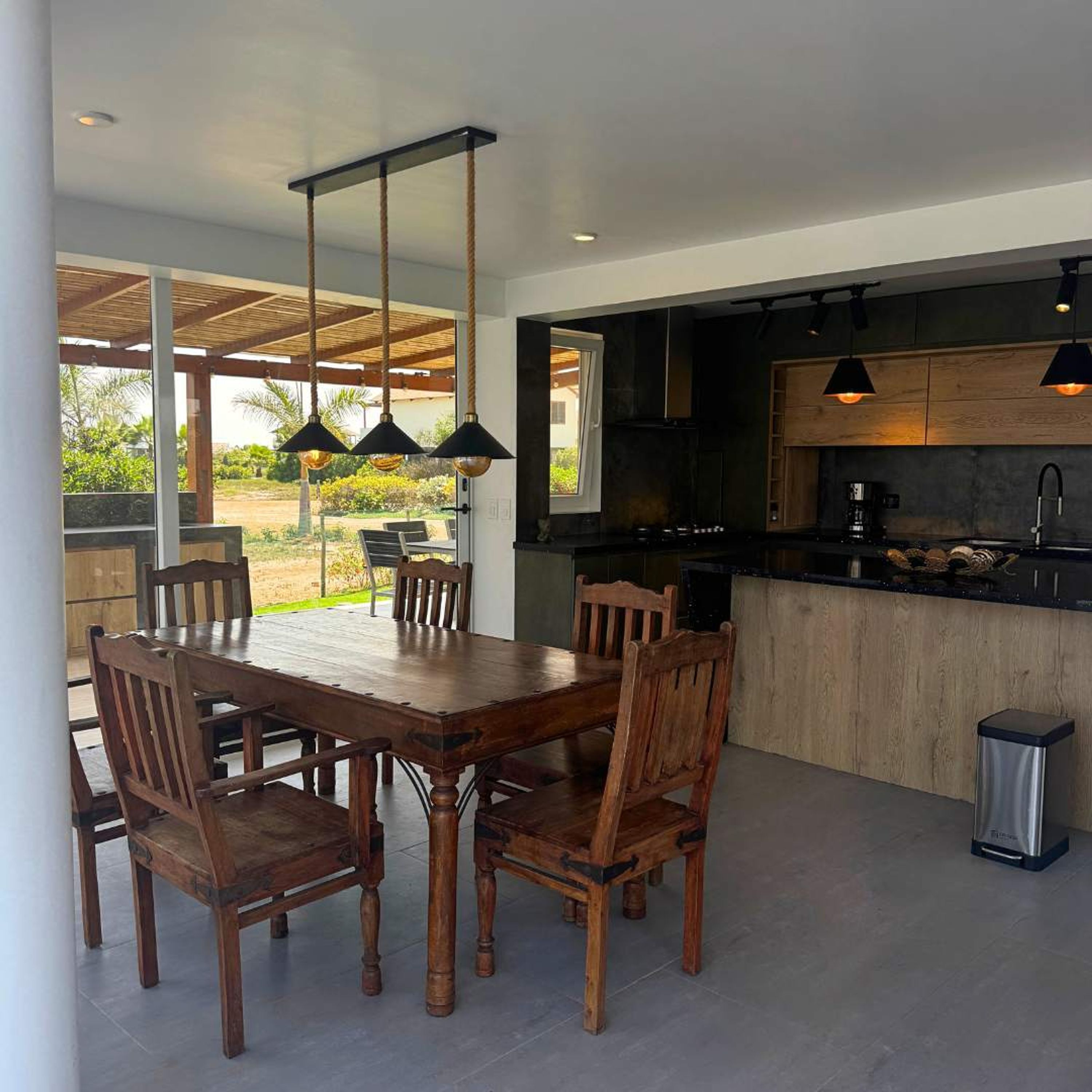 Une cuisine moderne avec un îlot central, une table à manger en bois et des chaises.