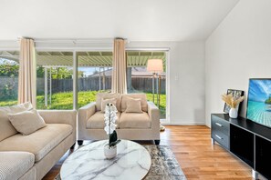 A living room with a beige sofa, a matching armchair, a marble coffee table, and a TV on a black stand. - Cozy Family Retreat With Fireplace Spacious Yard (Duarte)