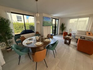 A dining area with a round table set for six, surrounded by teal chairs. There is a sofa and a coffee table in the living area. - 3BR Villa by Vistacana Rentals (Punta Cana)