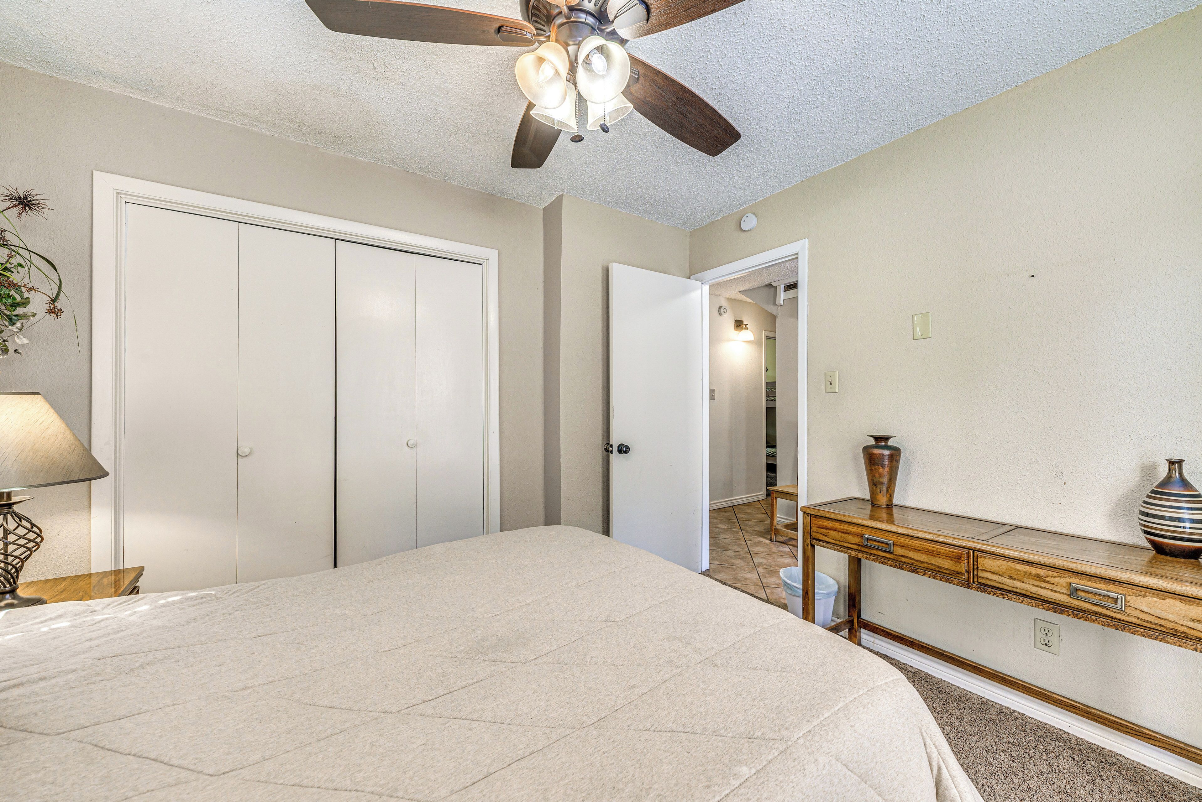 A bedroom with a bed, a desk, a ceiling fan, and a wardrobe.