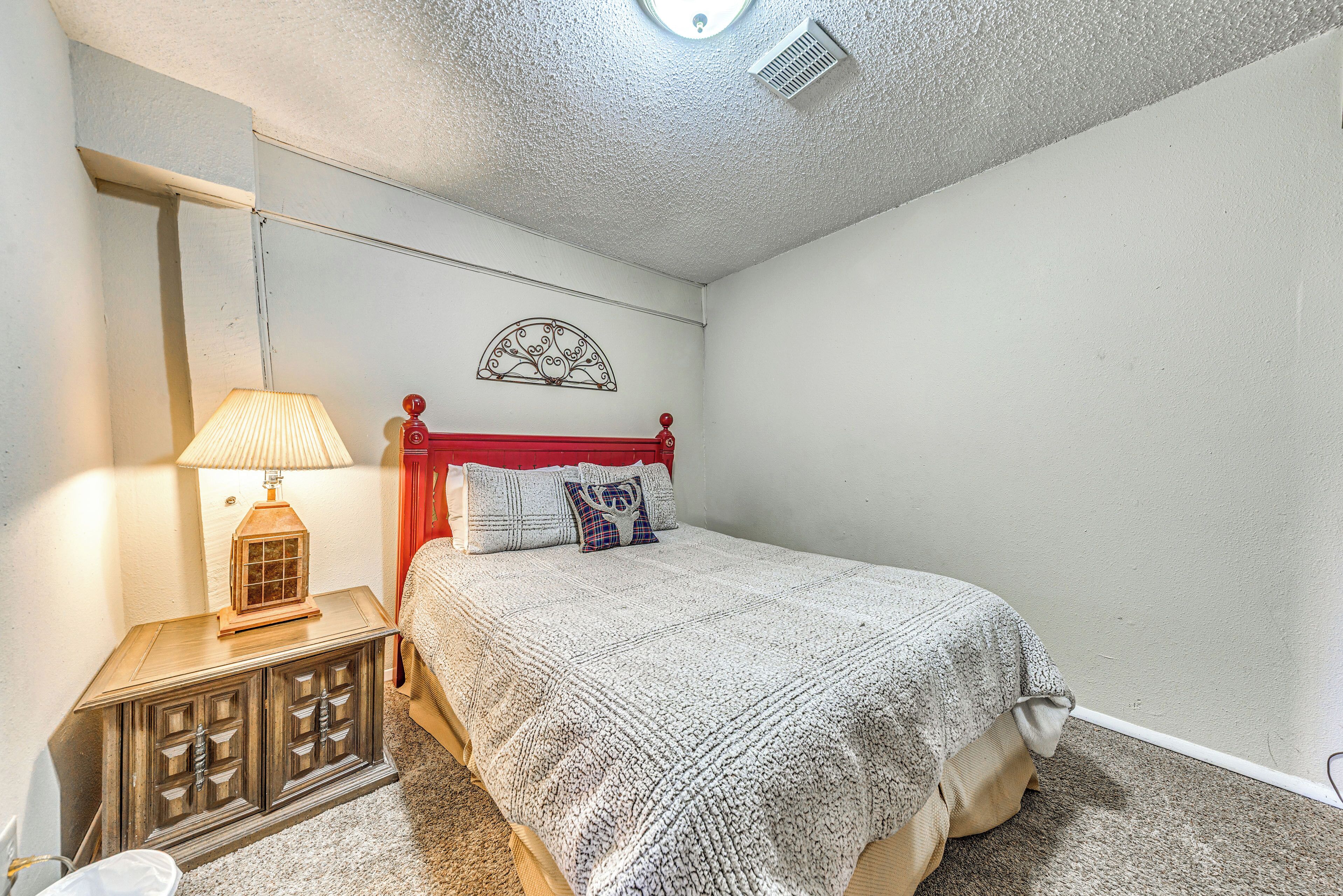 Una camera da letto con un letto, un comodino, una lampada e un elemento decorativo a parete.