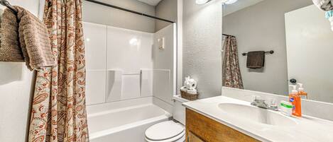 A bathroom with a bathtub, toilet, and a sink with a mirror.