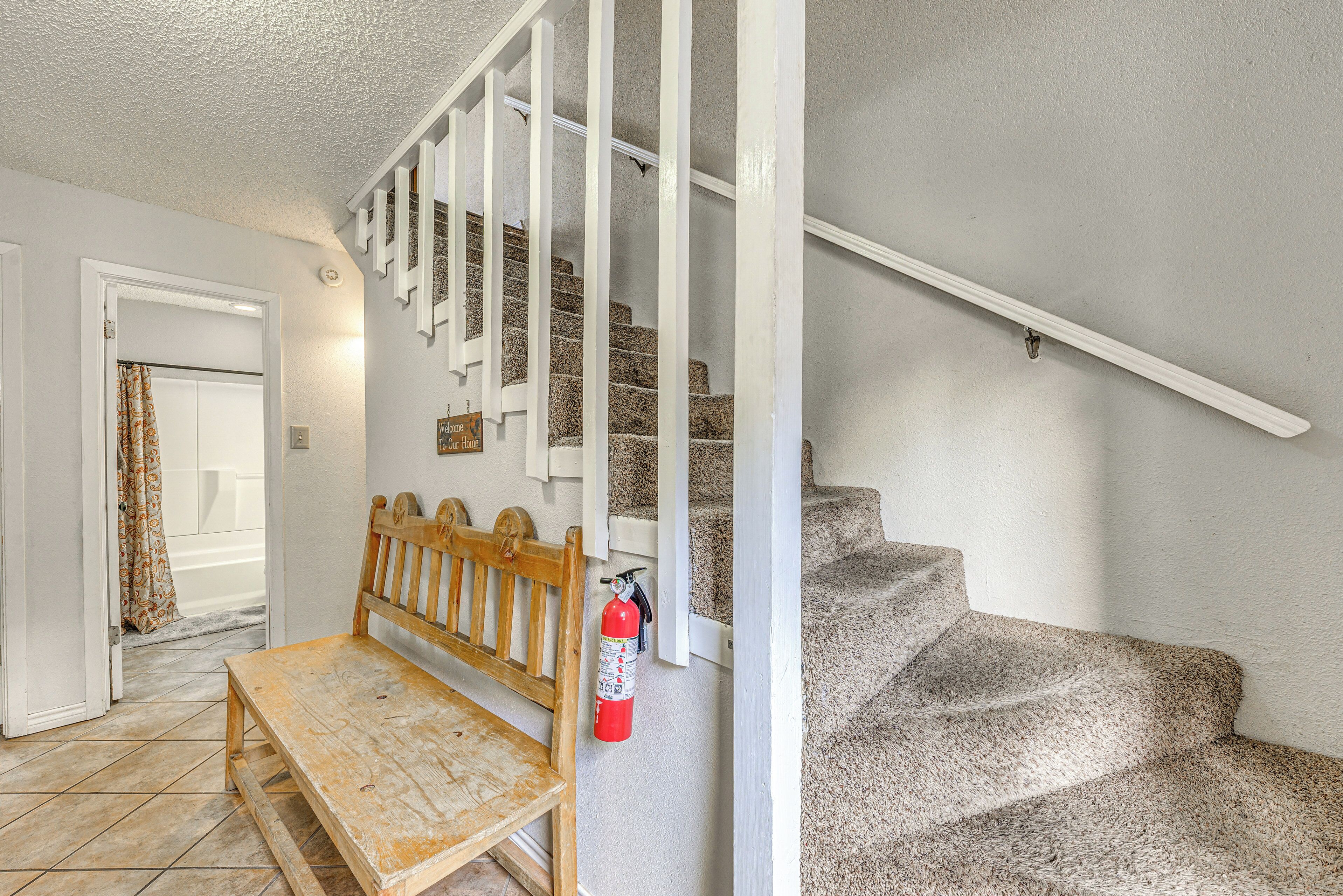 A staircase with white railings and a wooden bench at the bottom.