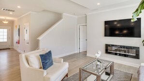 A modern living room with a white sofa, a glass coffee table, and a flat-screen TV mounted on the wall. - 3 Mi to Umstead State Park: Durham Home (Durham)