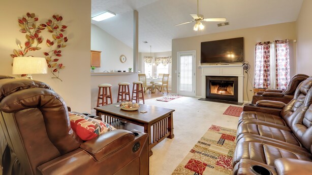 A living room with leather sofas, a fireplace, and a dining area with a chandelier. - 2 Mi to Heritage Park: Pet-friendly Mcdonough Home (McDonough)