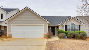 A single-story house with a garage, a front door, and a small front yard with a lawn and shrubs. - 2 Mi to Heritage Park: Pet-friendly Mcdonough Home (McDonough)