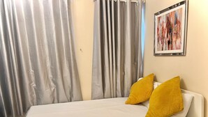 Une chambre d’hôtel avec un lit, des rideaux, un tableau et une table de chevet.