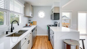 A modern kitchen with white cabinetry, a central island, a built-in oven, and a microwave. - Steps to Beach: Centrally Located OBX Home! (Kill Devil Hills)