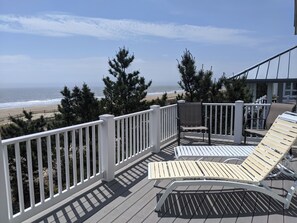 Eine Terrasse mit weißen Geländern, einem Liegestuhl und einem Tisch.