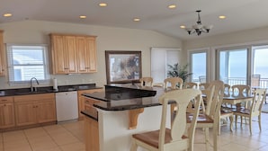 A kitchen with wooden cabinets, a built-in island, and a dining area with wooden chairs. - 5 Bedroom Oceanfront on a private beach (Bethany Beach)