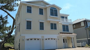 A two-story building with a garage, a balcony on the second floor, and a small porch area. - 5 Bedroom Oceanfront on a private beach (Bethany Beach)