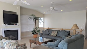 A living room with a sofa, armchairs, a coffee table, a TV, a fireplace, and a ceiling fan. - 5 Bedroom Oceanfront on a private beach (Bethany Beach)
