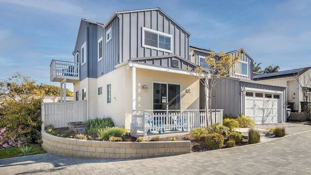 A modern two-story house with a garage, a covered porch, and a landscaped garden.
