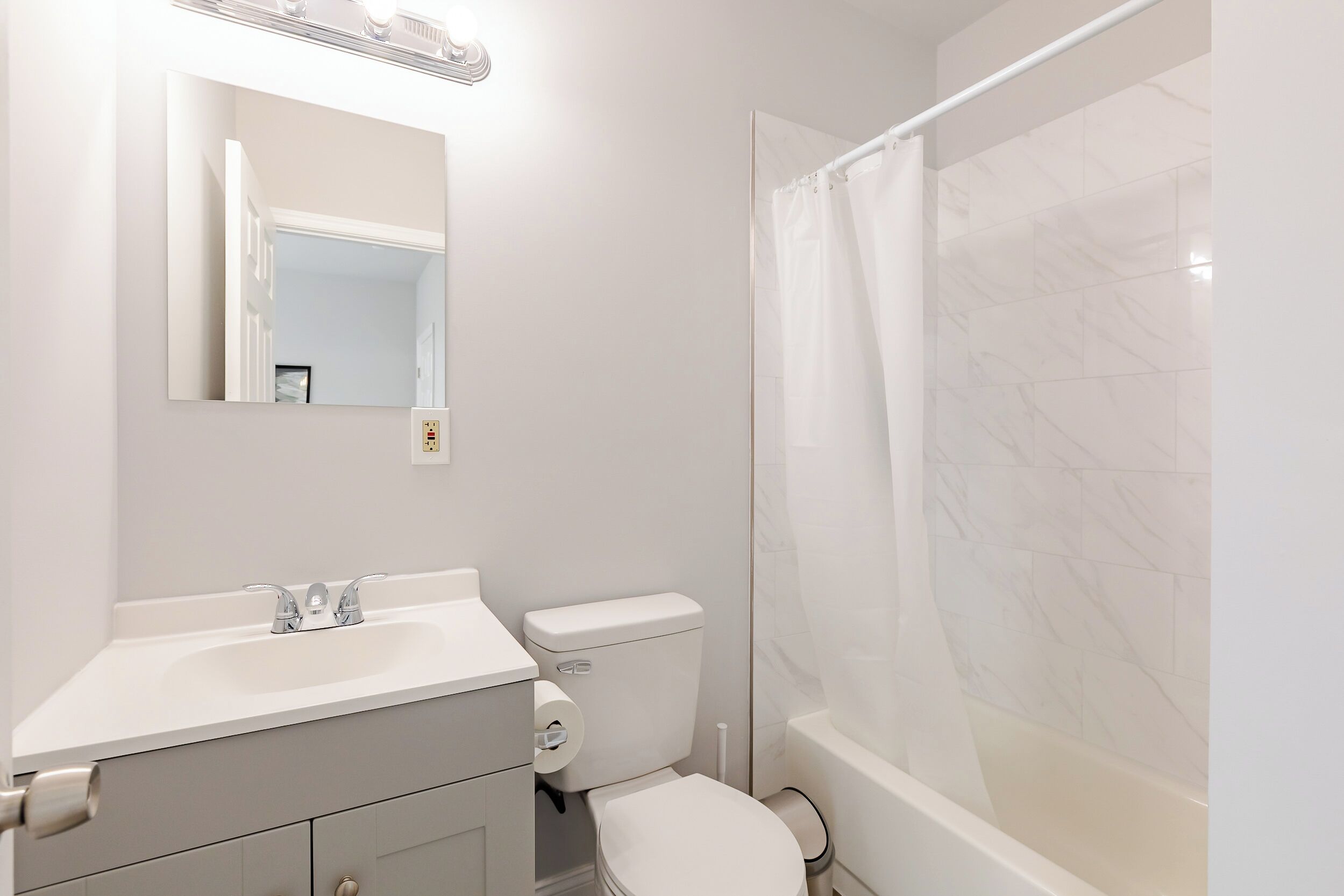 Un baño con inodoro, lavabo, espejo y cortina de ducha.