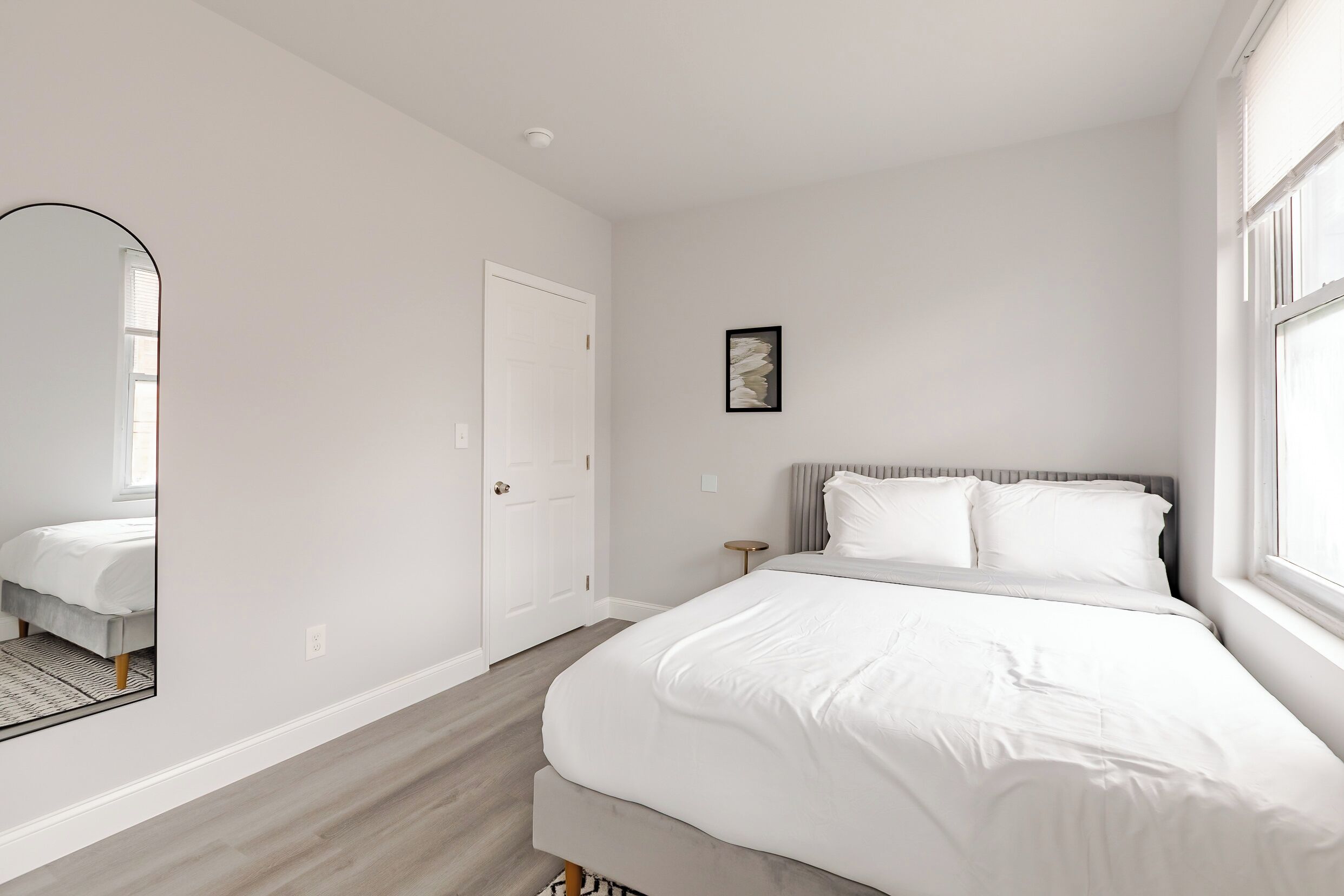 Un dormitorio con una cama grande, una mesita de noche, un espejo y una puerta.