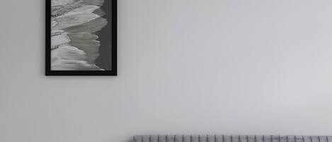 A bedroom with a bed, a bedside table, a framed picture on the wall, and a radiator.