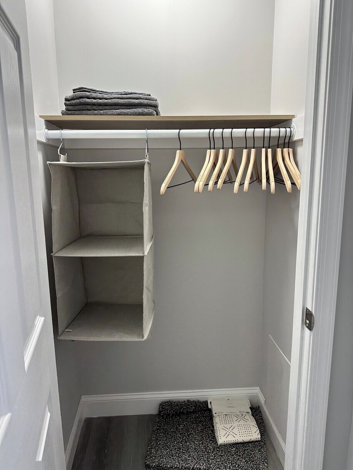 A walk-in closet with open shelving, a hanging rod, and a small rug.
