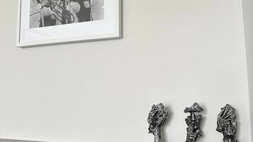 Fotografía en blanco y negro enmarcada de una banda de música de bronce sobre una pared, con tres esculturas metálicas en un estante negro debajo.