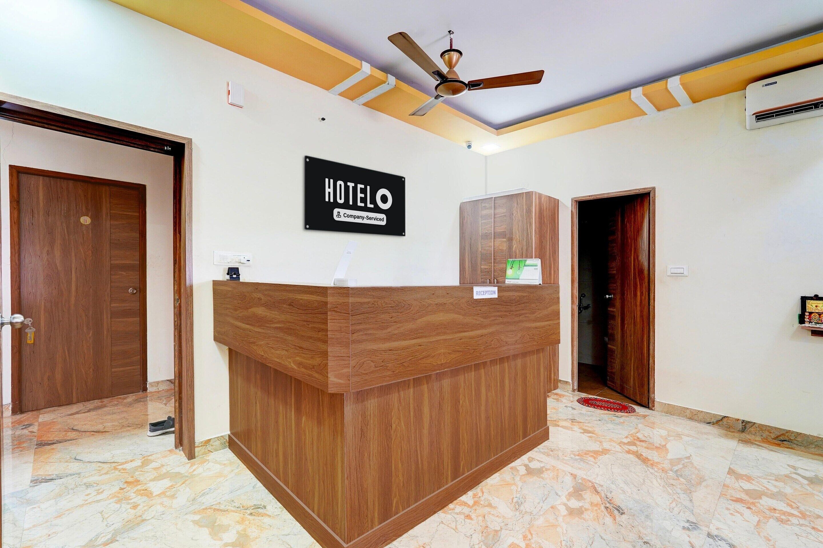 A hotel reception desk with a wooden finish, a ceiling fan, and a sign that reads "HOTEL".