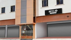 Un hotel moderno con un letrero que dice "HOTELO", una fachada vertical naranja y gris, y persianas cerradas en la planta baja.