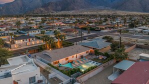 Zona residencial con casas, piscina y montañas al fondo.