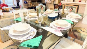 Une table à manger dressée avec des assiettes, des verres et des couverts, avec un canapé et un téléviseur en arrière-plan.