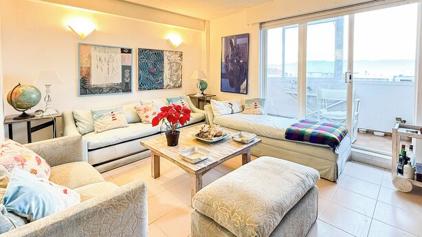 Un salon spacieux comprenant un canapé, des fauteuils, une table basse et un balcon avec vue.