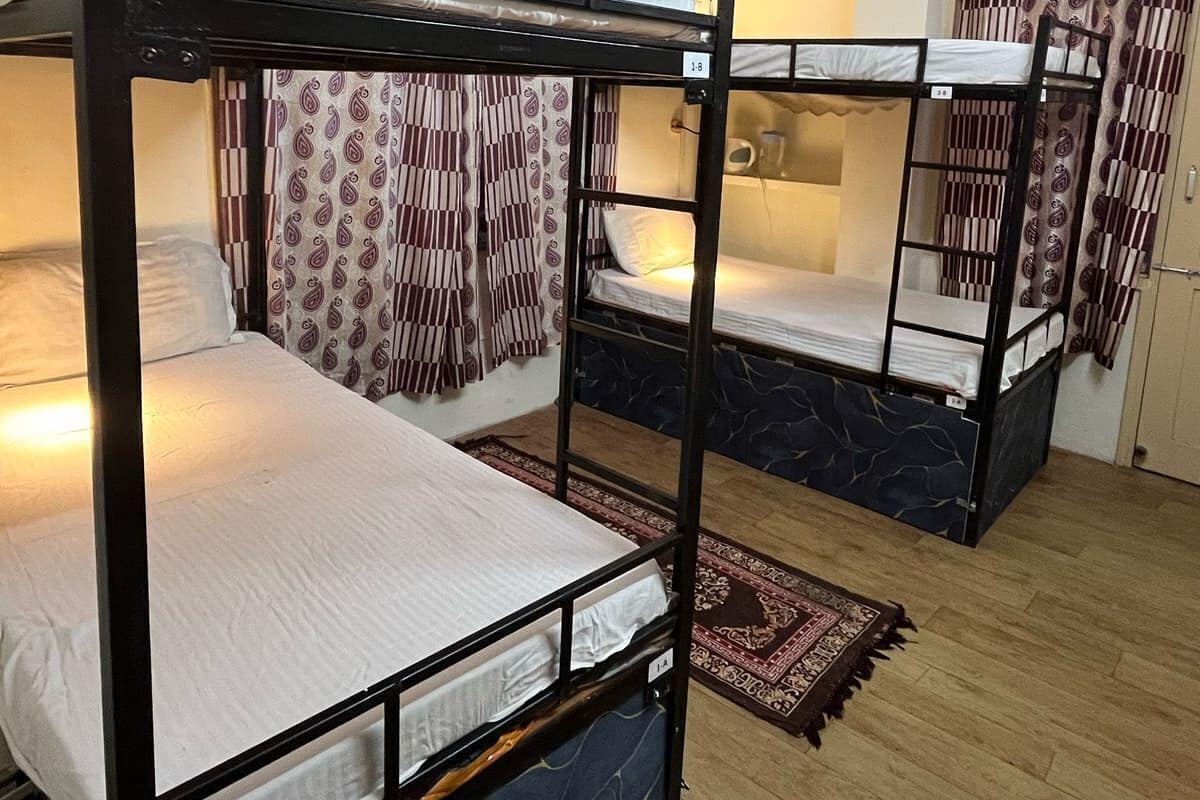 Un dormitorio con literas, cortinas estampadas y suelo de madera.