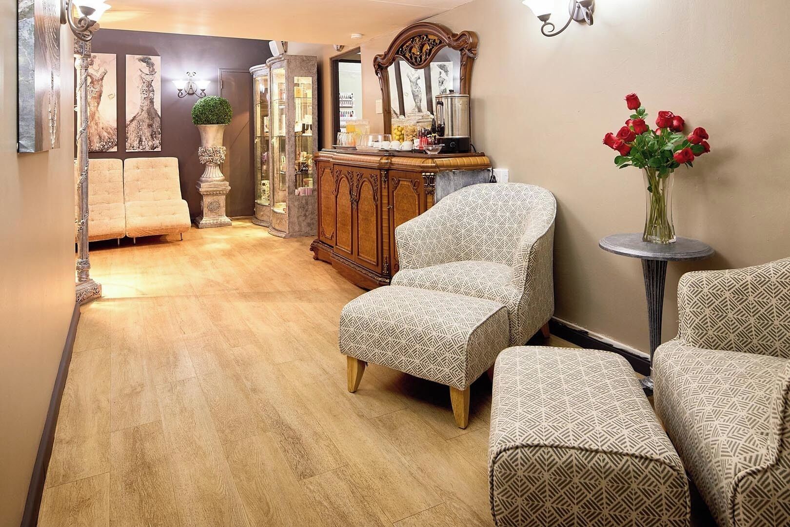 A hallway with patterned armchairs, a wooden cabinet, and a vase with red roses.