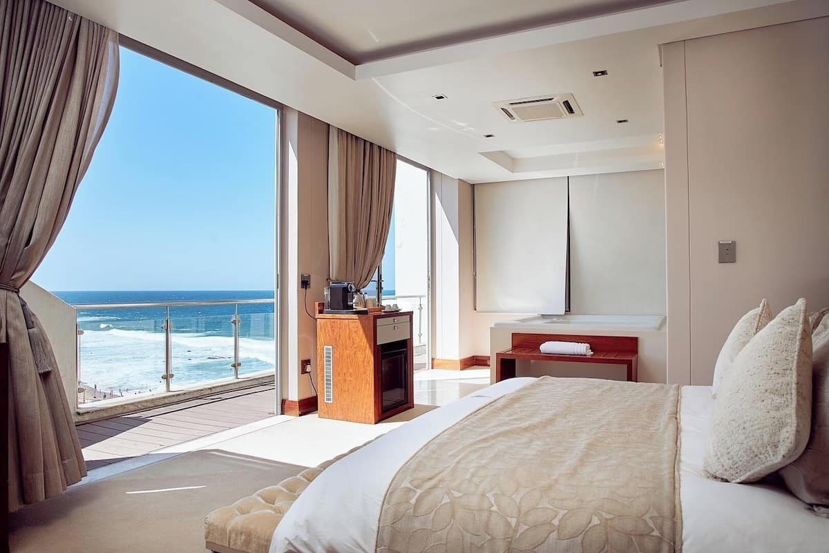 Ein Hotelzimmer mit einem großen Bett, einem Schreibtisch und Meerblick.