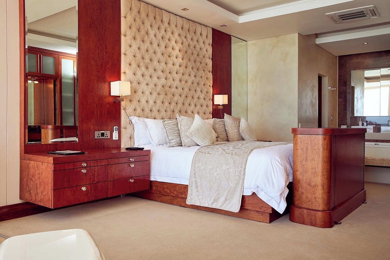 A bedroom with a large bed, wooden dresser, and a mirror.