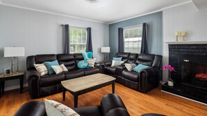 A living room with two leather sofas, a wooden coffee table, and a fireplace.