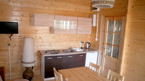 A wooden cabin interior with a kitchen area, dining table, and chairs. - Single-storey Homes by the Lake, Jelen (Borne Sulinowo)