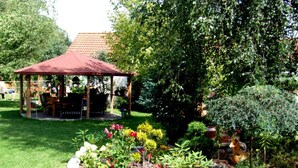 A garden with a gazebo, various plants, and a statue. - Single-storey Homes by the Lake, Jelen (Borne Sulinowo)