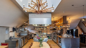 Une cuisine spacieuse dotée d’un îlot central, d’appareils électroménagers en acier inoxydable et d’un lustre en bois.