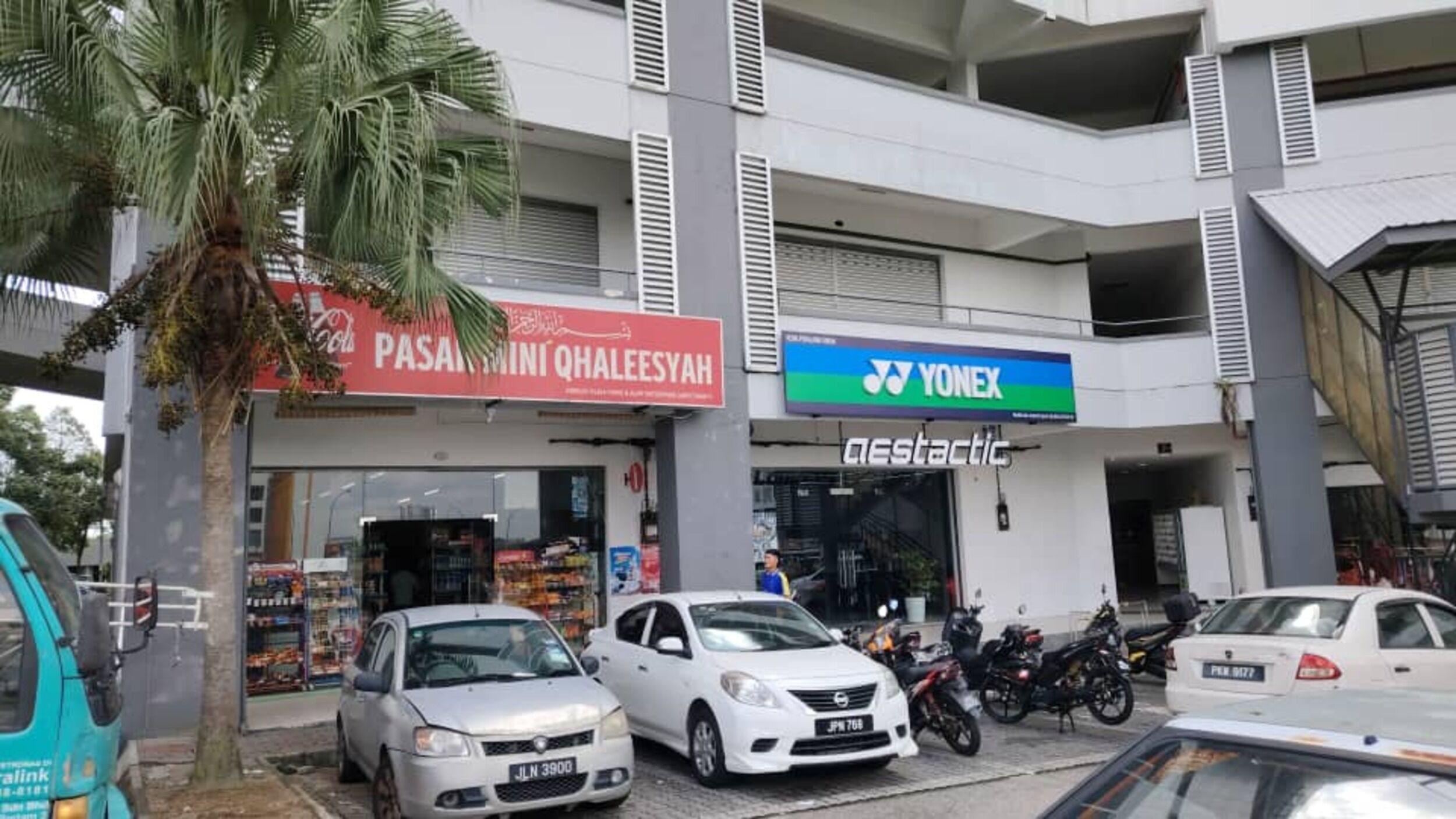Un immeuble commercial doté de plusieurs devantures de magasins, notamment une pharmacie et un fournisseur de services de télécommunications.