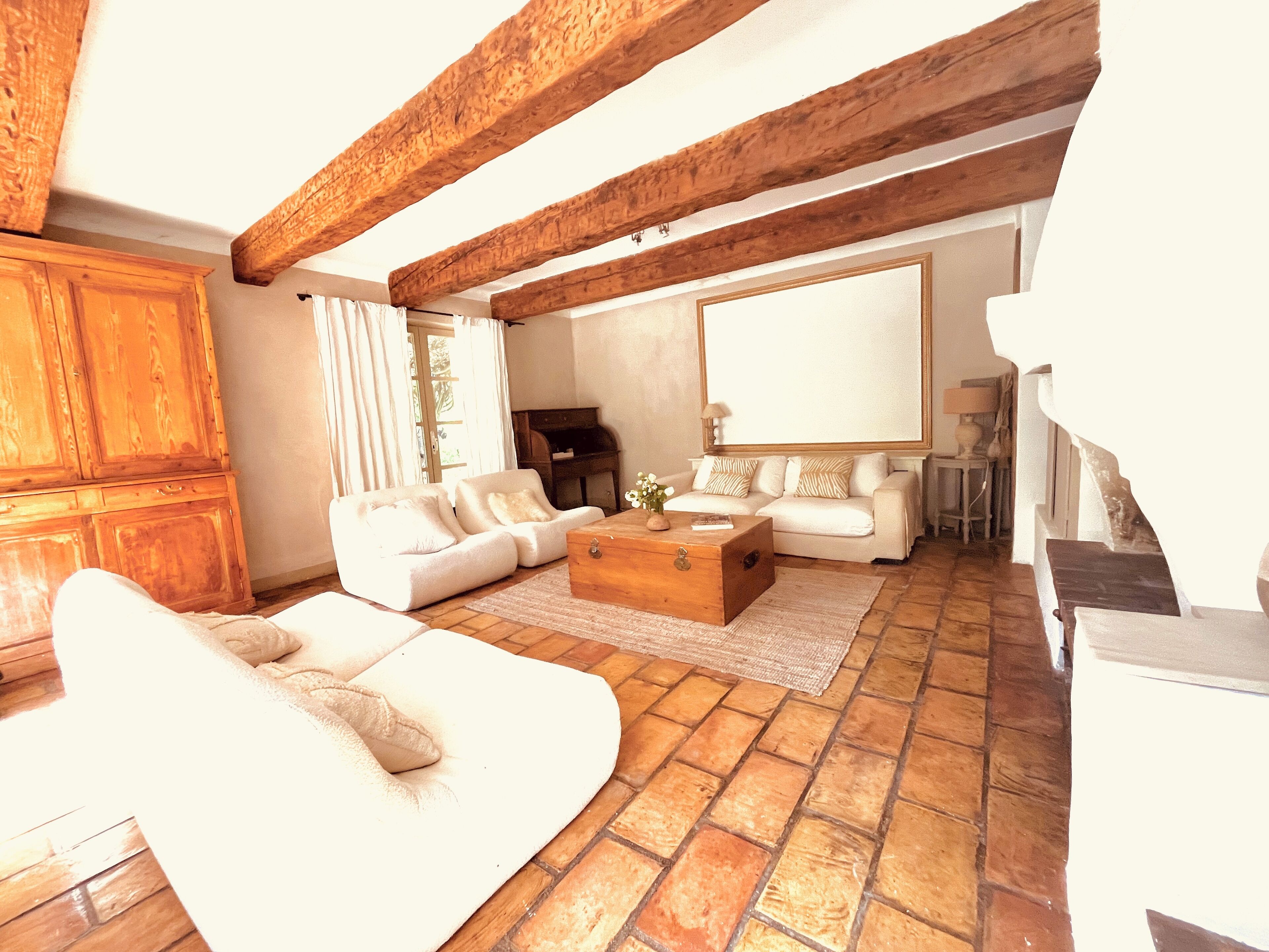 A spacious living room with a white sofa set, a wooden coffee table, and a fireplace.