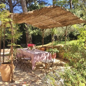 Enjoy al fresco dining under a shaded canopy surrounded by lush greenery and vibrant flowers.