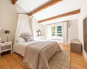 A bedroom with a bed, bedside table, lamp, and a window with curtains.
