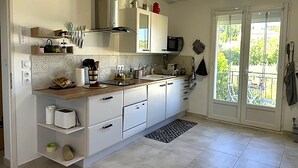 A modern kitchen with white cabinets, a microwave, and a large window.