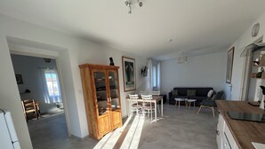 A spacious living area with a dining table, chairs, a sofa, and a kitchen area with cabinets and a countertop.