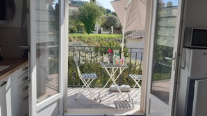 A balcony with a table and chairs, a small garden, and a view of a residential area.