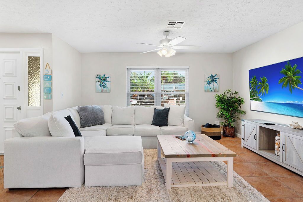 A modern living room with a white sofa, a coffee table, and a TV on a cabinet.