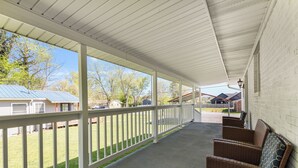 A covered porch with wicker furniture and a view of a residential area. - Country Charmer (Sevierville)