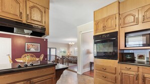 A kitchen with wooden cabinets, a black countertop, and a stainless steel oven. - Country Charmer (Sevierville)