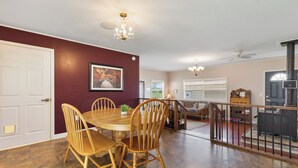 A dining area with a wooden table and chairs, a chandelier, and a view of the living room. - Country Charmer (Sevierville)