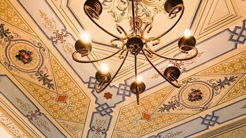 A ceiling with a chandelier and ornate patterns.