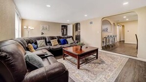 A living room with a sectional sofa, a coffee table, and a rug. There is a dining area visible through an archway. - dog-friendly home with fenced yard, grill, sunroom (San Antonio)